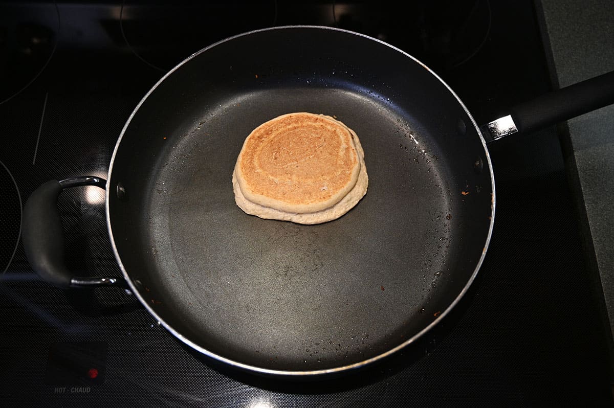 Image of a pancake being cooked in a frying pan on the oven.