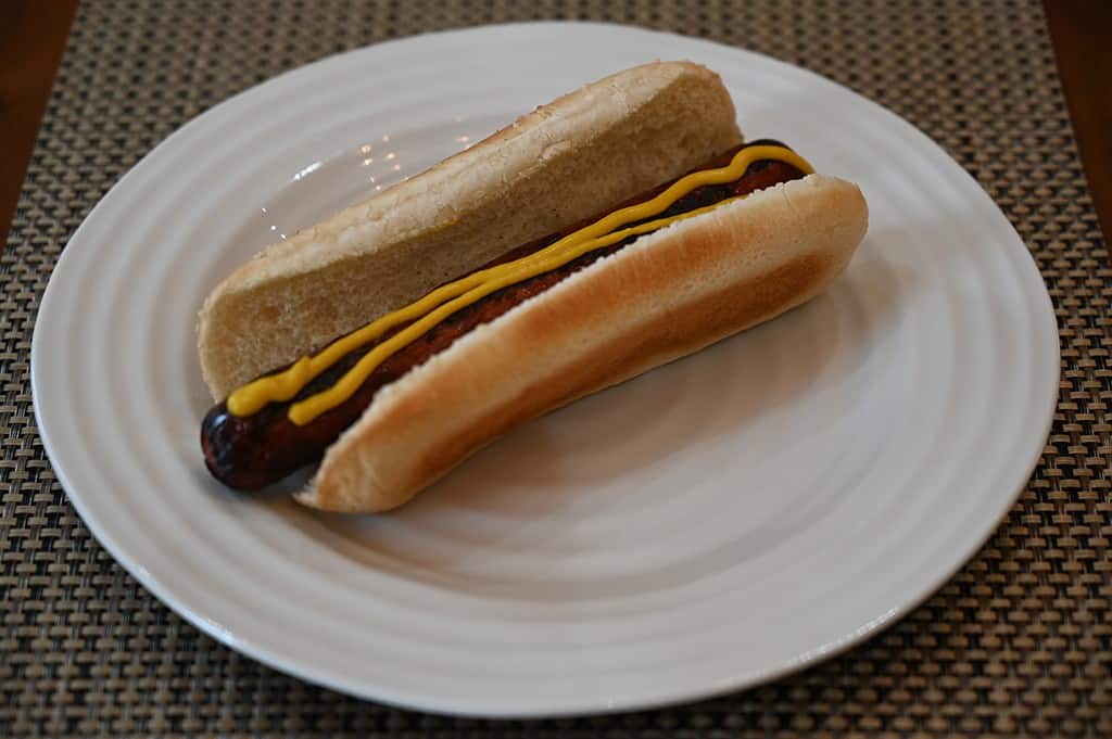 Costco hot dog with mustard and on a white plate. 