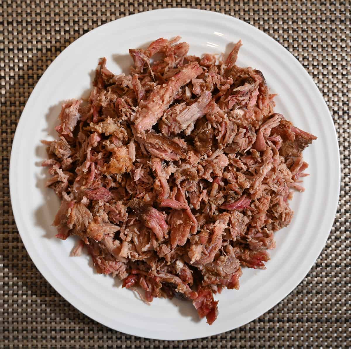 Top down image of the cooked pulled pork served on a white plate.