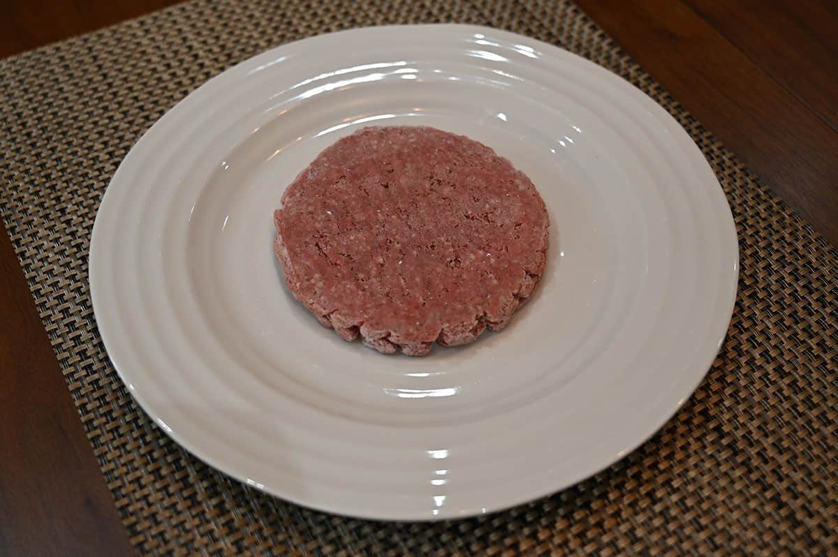 Image of one Costco beef sirloin patty frozen still and on a white plate. 