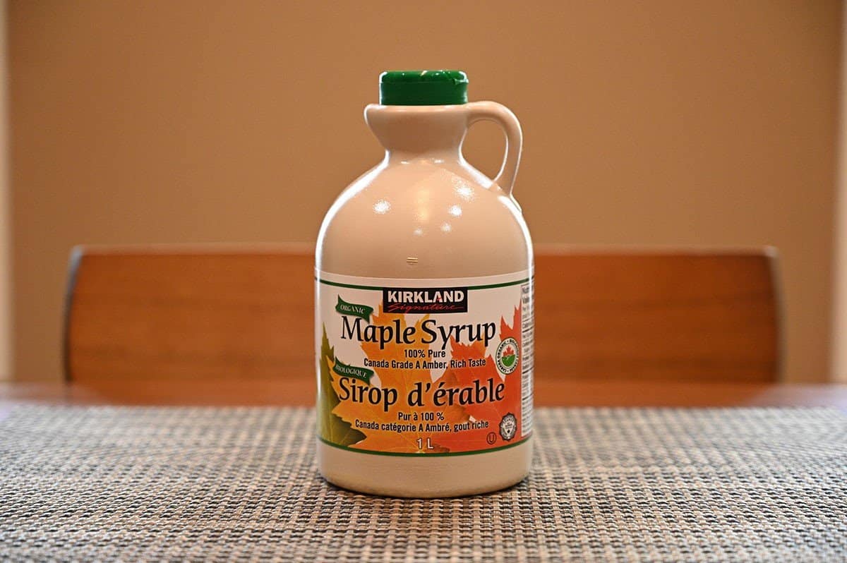 Image of a bottle of Costco Kirkland Signature Maple Syrup sitting on a table. 