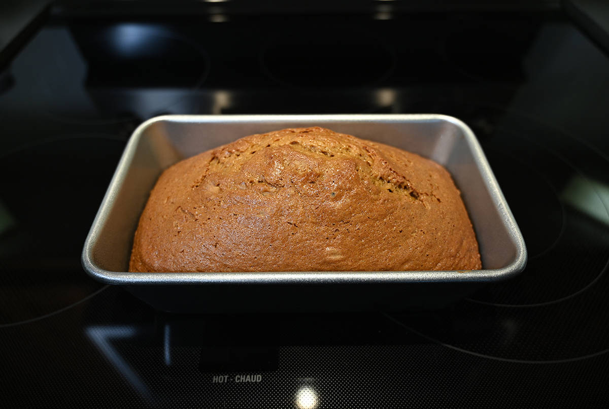 Image of a baked pumpkin spice loaf sitting in the loaf pan on the stove.
