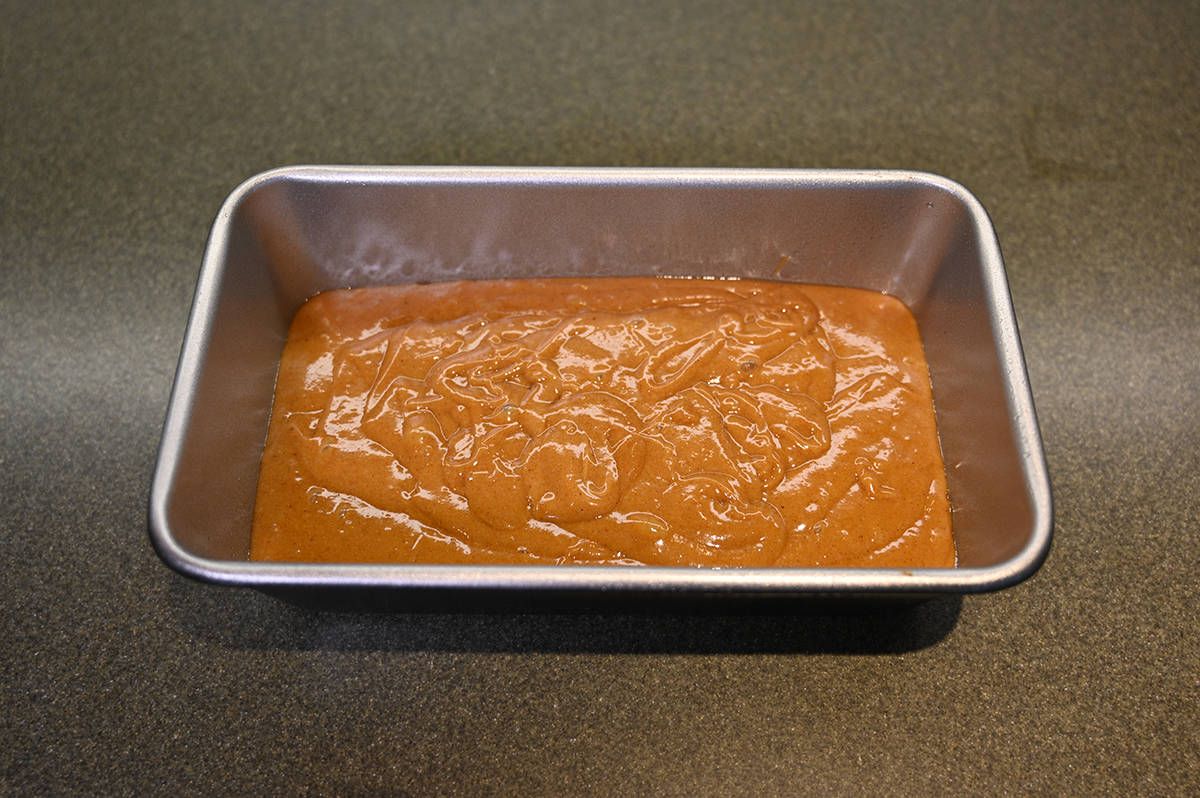 Top down image of a loaf pan filled with pumpkin spice loaf batter. 