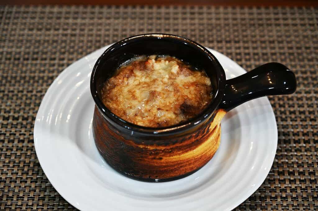 Costco Cuisine Adventures French Onion Soup soup prepared in a soup bowl and served on a white plate. 