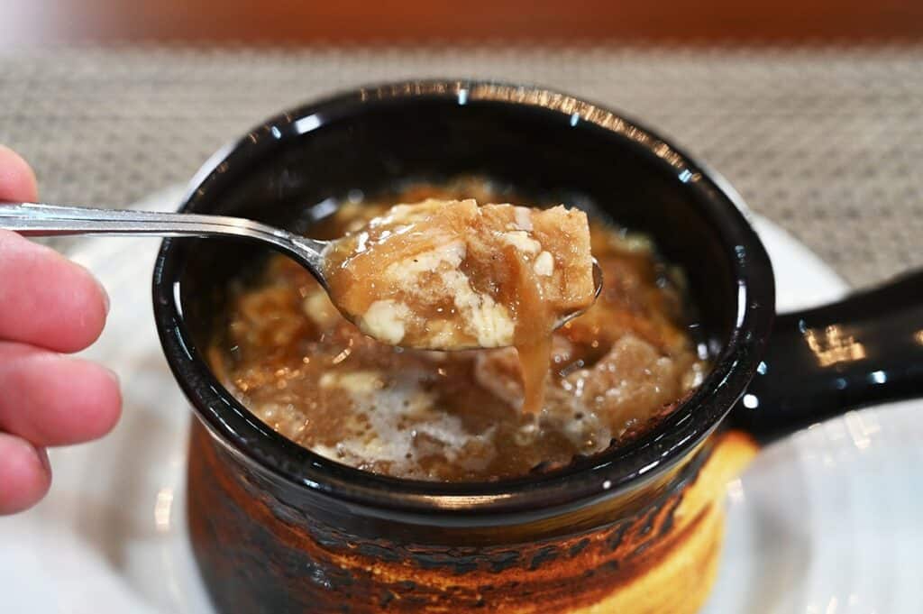 Costco Cuisine Adventures French Onion Soup prepared in a soup bowl closeup image of a spoonful of soup. 