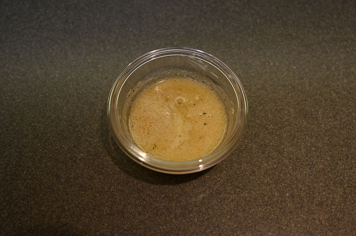 Top down image of prepared garlic butter melted and in a clear bowl ready for brushing on the biscuits.