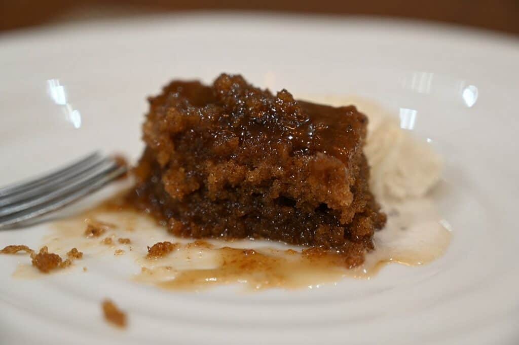 Close up Image of a piece of the Costco The Sticky Toffee Pudding Co. Sticky Toffee Pudding plated with vanilla ice cream beside it. 