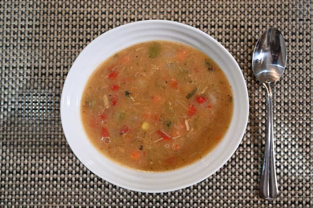 Top down image of a white bowl containing prepared chicken tortilla soup. 