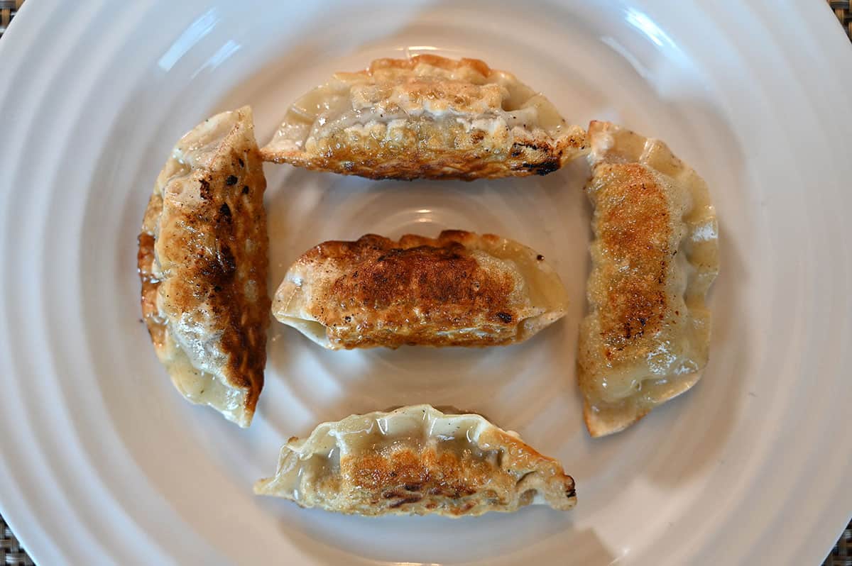 Five cooked Costco Bibigo Beef Bulgogi Mandu on a white plate top down image.