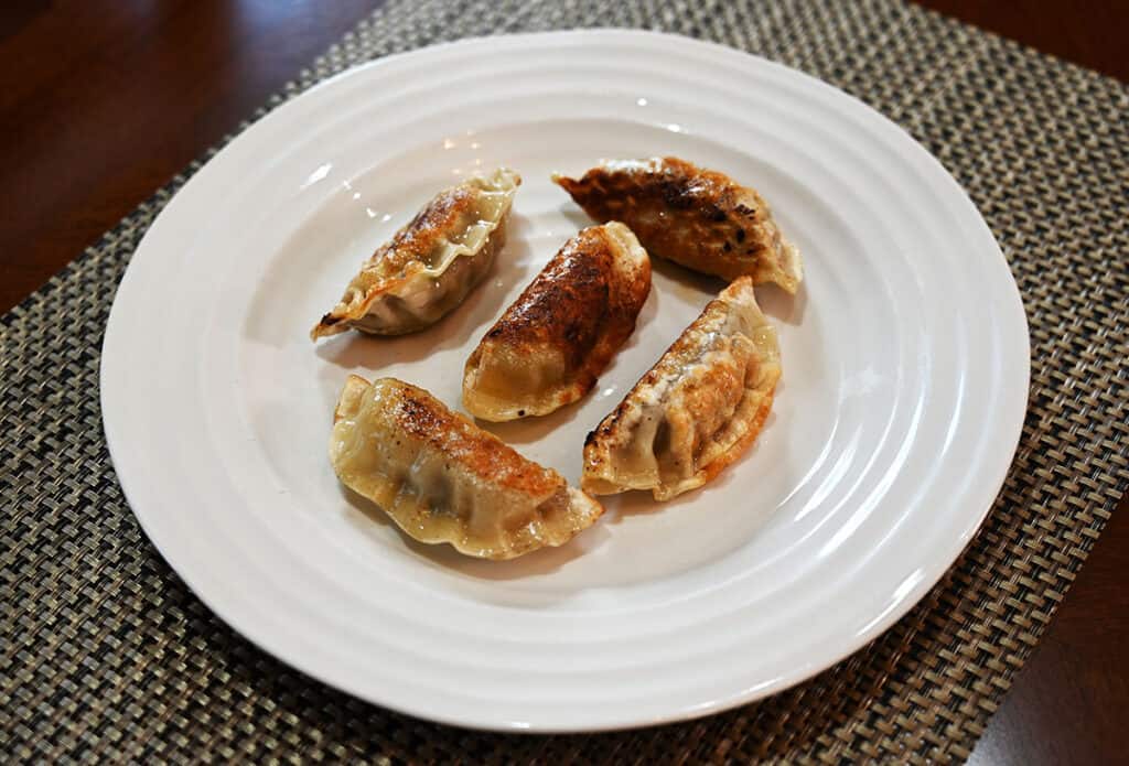 Five cooked Costco Bibigo Beef Bulgogi Mandu on a white plate.