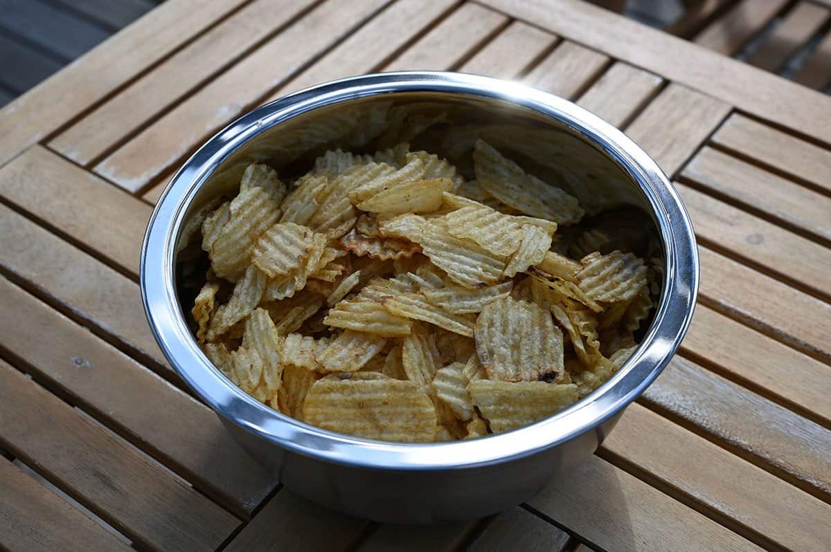 Costco Kirkland Signature Kettle Brand Potato Chips poured into a stainless steel bowl and sitting on a deck. 