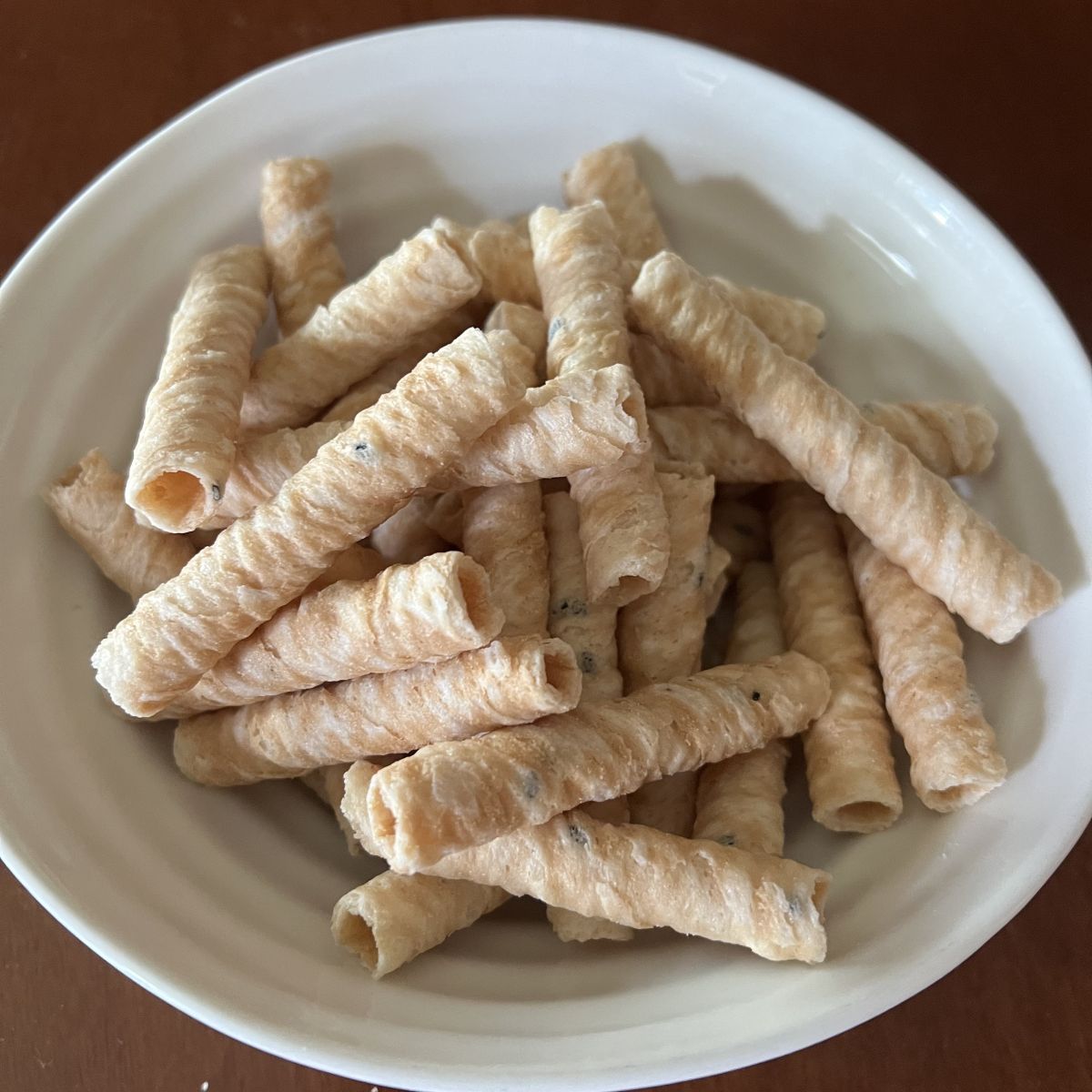 Closeup image of a bowl of crispy coconut rolls. 