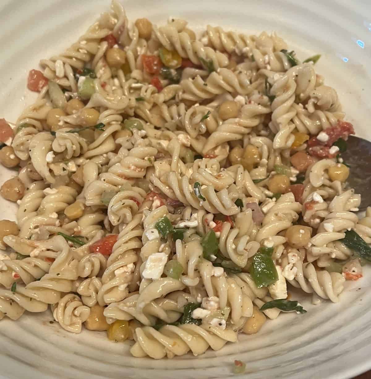 Very closeup image of the pasta salad showing all the ingredients in it like chickpeas, tomatoes.
