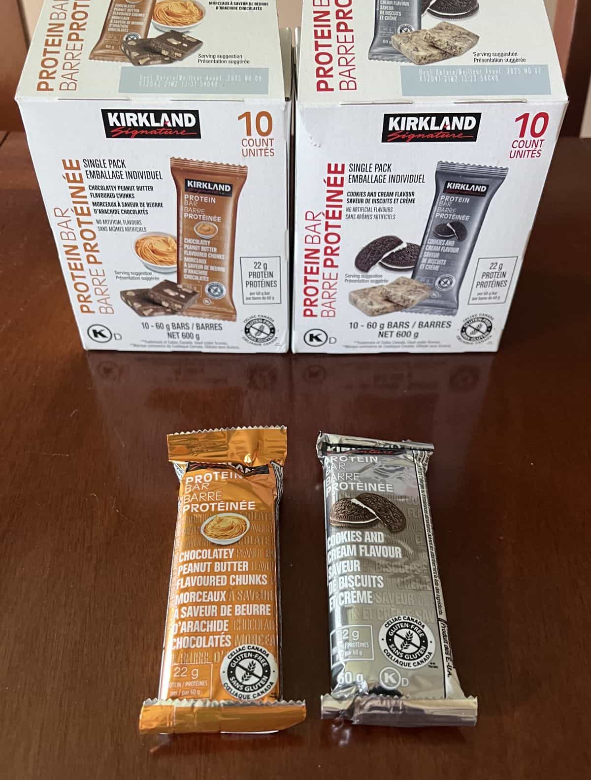 Image of two protein bars unwrapped sitting on a table, one chocolate peanut butter, one cookies and cream.