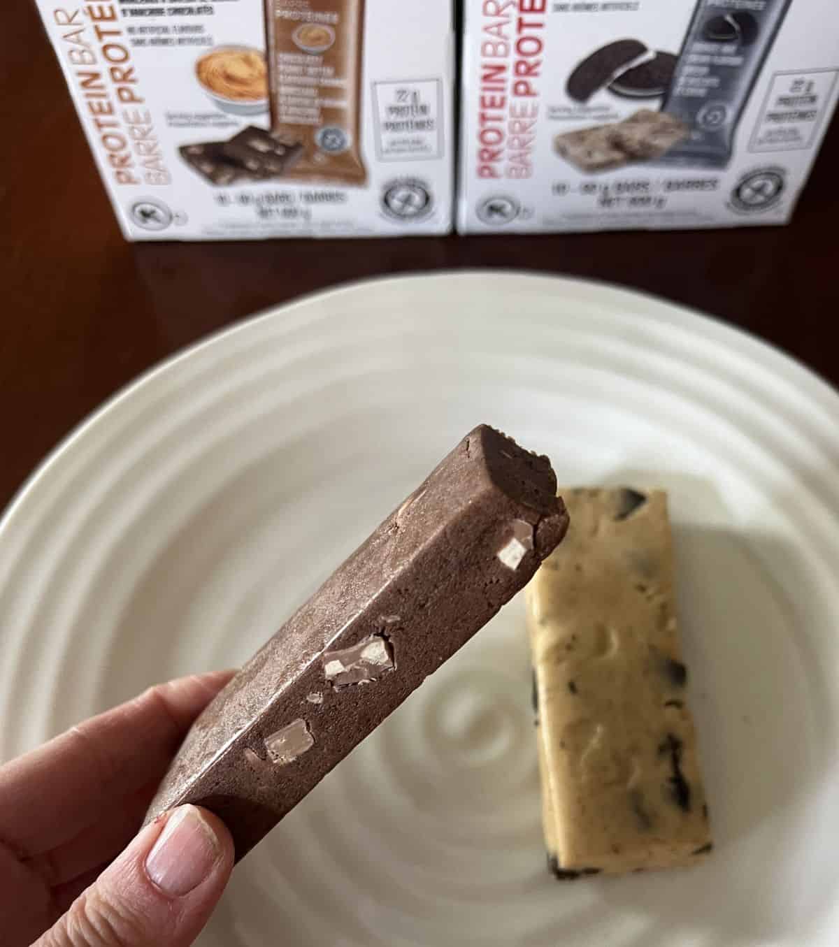 Closeup of a hand holding the chocolaty peanut butter flavored chunks protein bar close to the camera. 