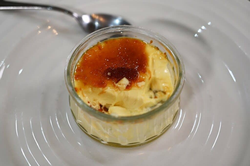 One Costco Marie Morin Crème Brûlée prepared and on a white plate, half eaten. Closeup image. 