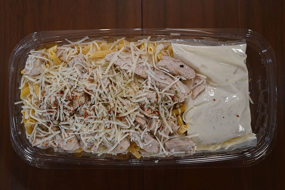 Costco Kirkland Signature Chicken Penne Alfredo tray sitting on a table, with the lid off top down image. 