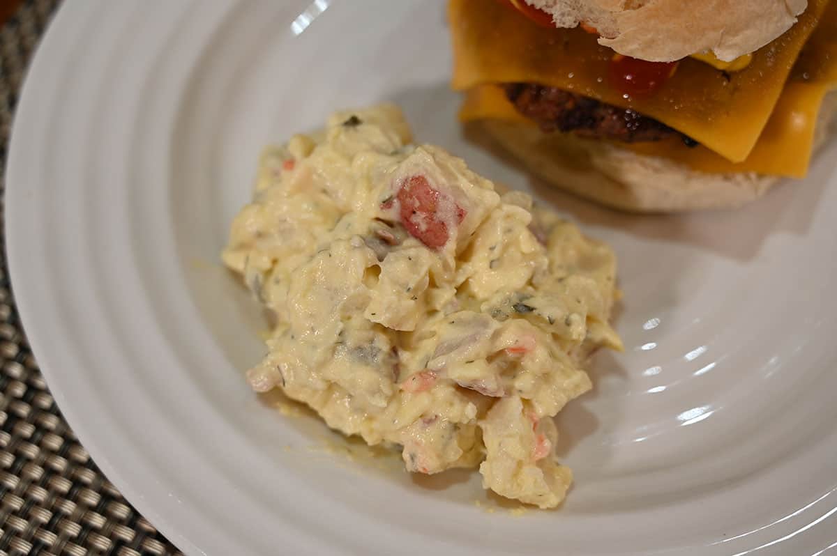 Costco Stonemill Kitchens Homestyle Red Potato Salad served on a white plate beside a hamburger, close up image of the potato salad.