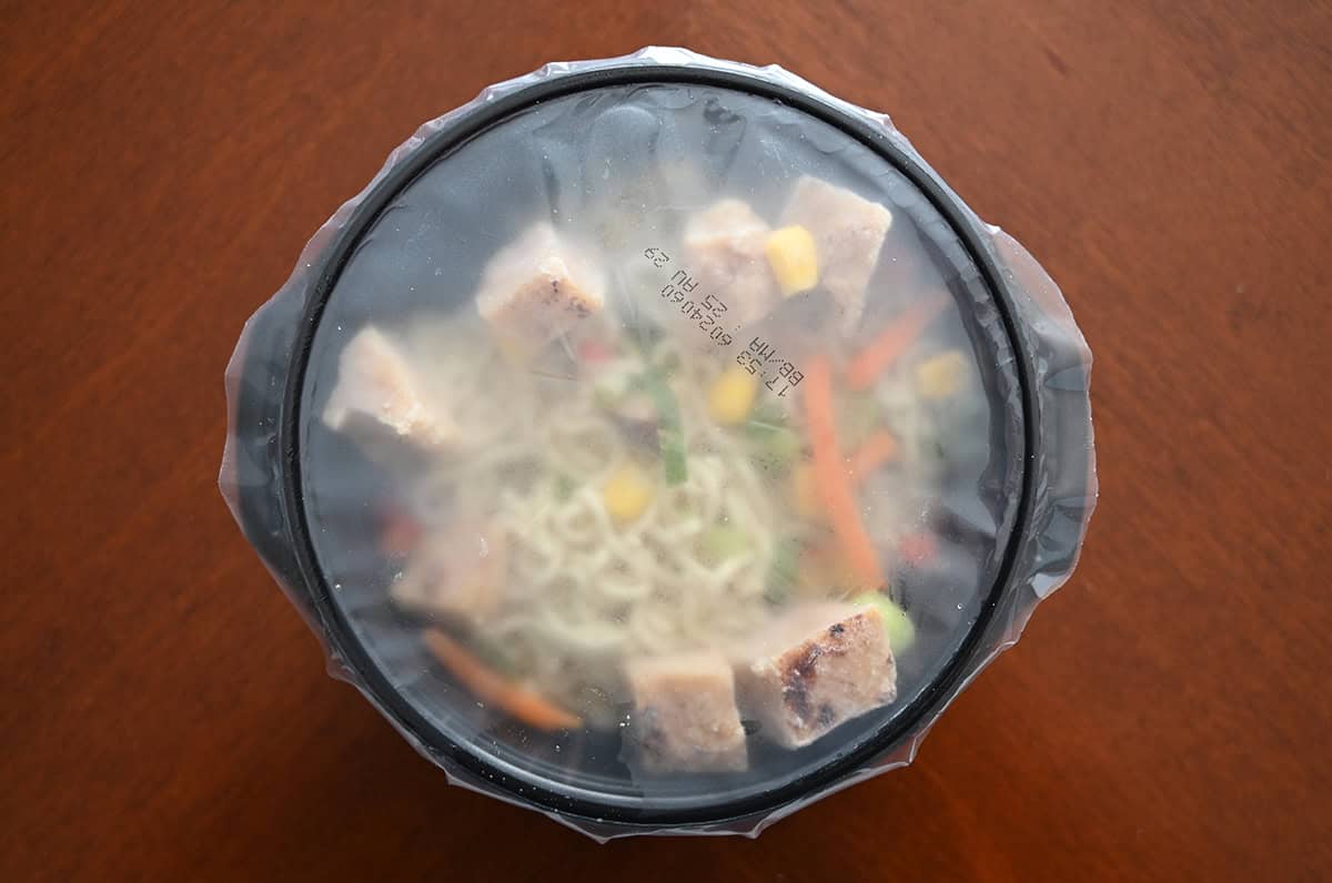 Top down image of a sealed bowl of frozen ramen sitting on a table.