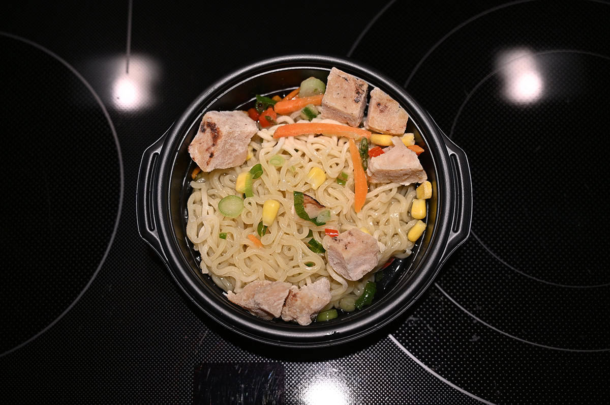 Top down closeup image of a bowl of ramen cooked and sitting on a stovetop.