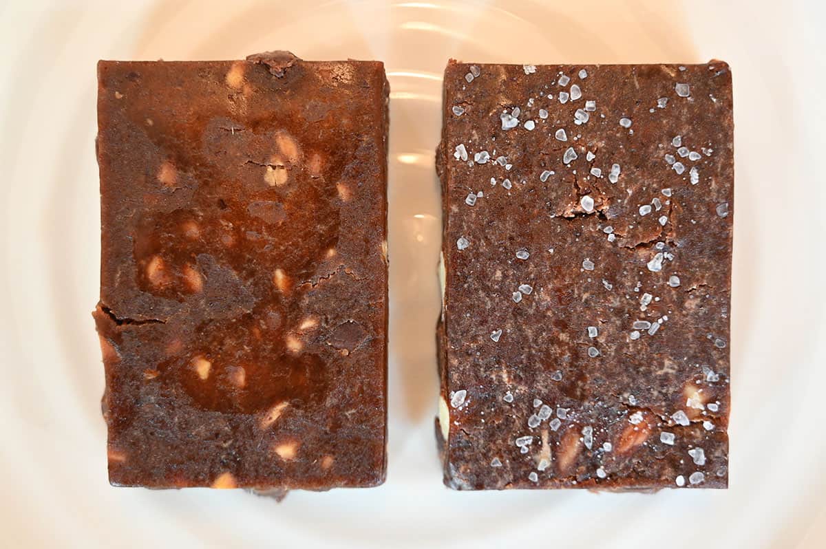 A close-up of two unwrapped RXBARs - one of each kind in the box. Peanut butter chocolate on left and chocolate sea salt on right. Unwrapped on a white plate.