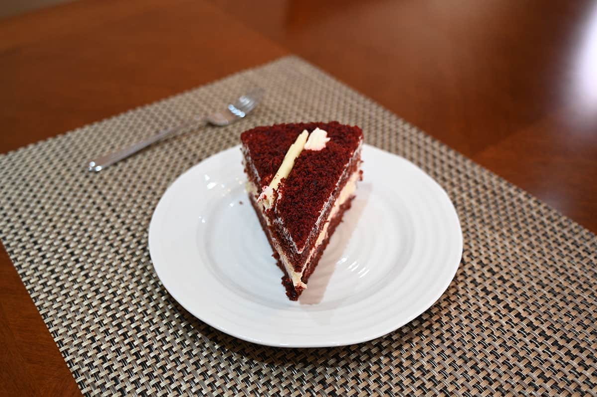Top down image of one slice of red velvet cheesecake served on a white plate with a fork beside it.