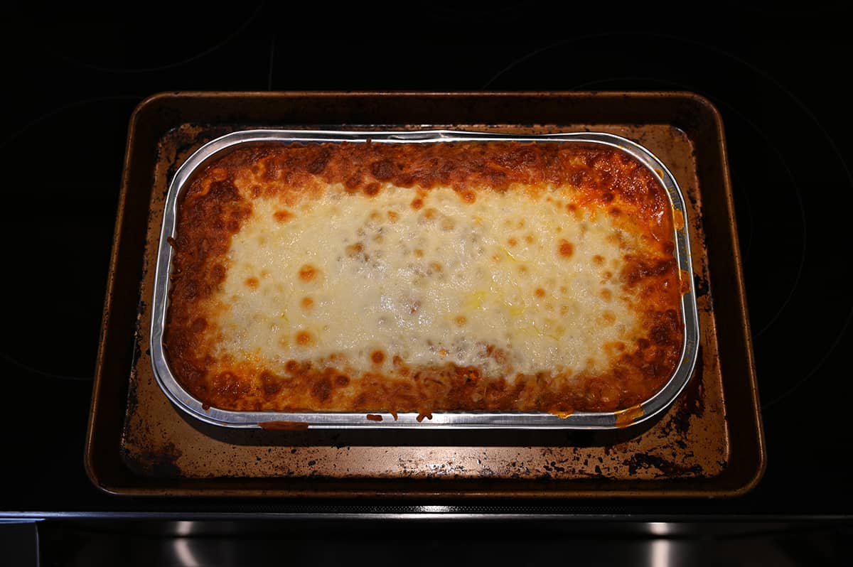 Top down image of a baked lasagna sitting on a stovetop sitting on a cookie tray.