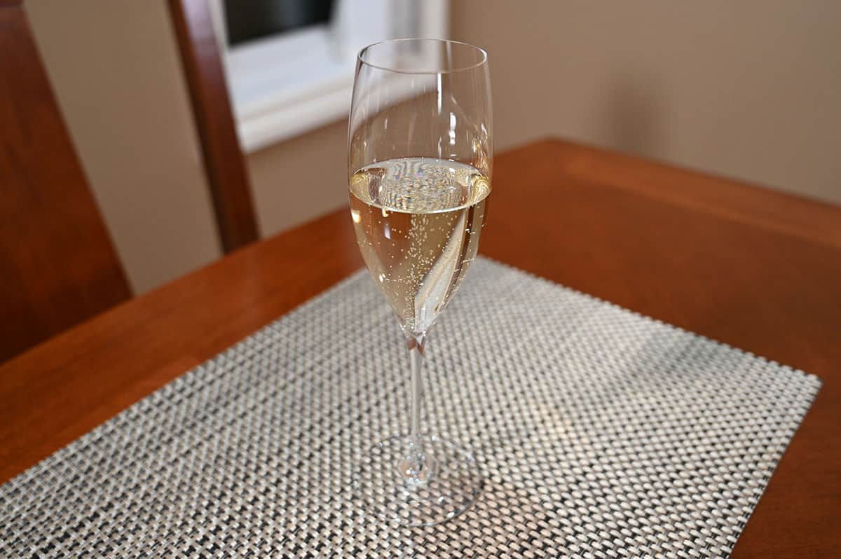 Image of a poured glass of prosecco sitting on a table, top down image.