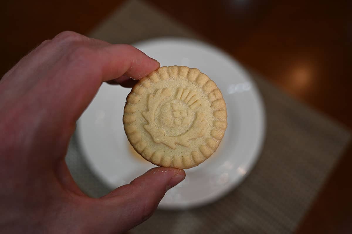 Image of a hand holding one shortbread thistle round cookie.