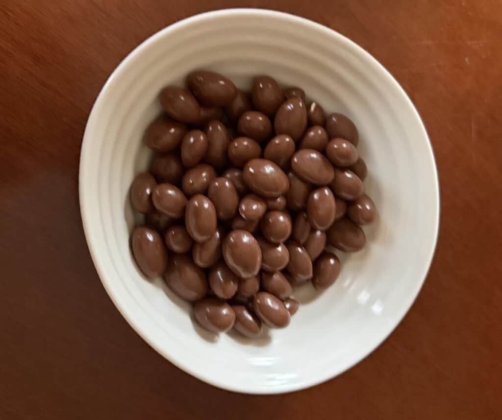 Top-down image of a bowl of chocolate covered almonds.