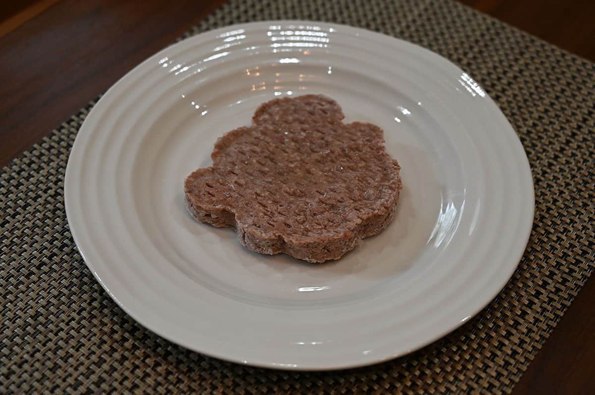 The Keg Prime Rib Beef Burgers frozen before cooking on a white plate. 