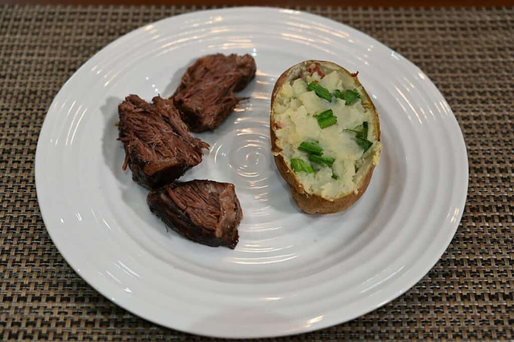 Costco 44th Street Beef Pot Roast pieces of pot roast on a white plate with a baked potato beside it. 