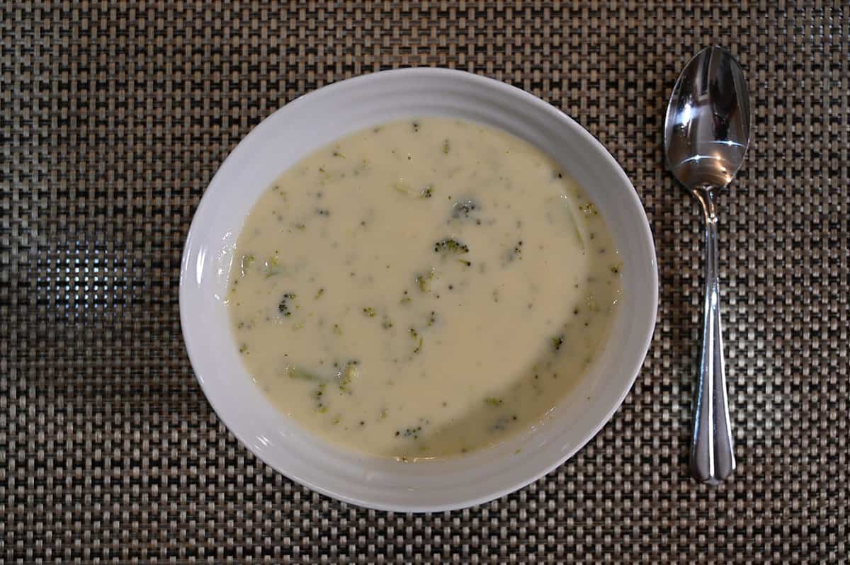 Top down image of a bowl of prepared soup with a spoon beside it.