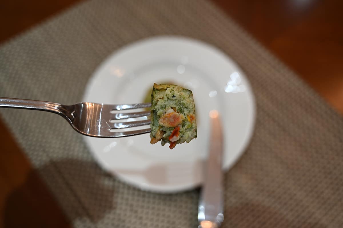 Closeup image of a fork with a bite of the frittata on it so you can see the center of the frittata with the veggies.
