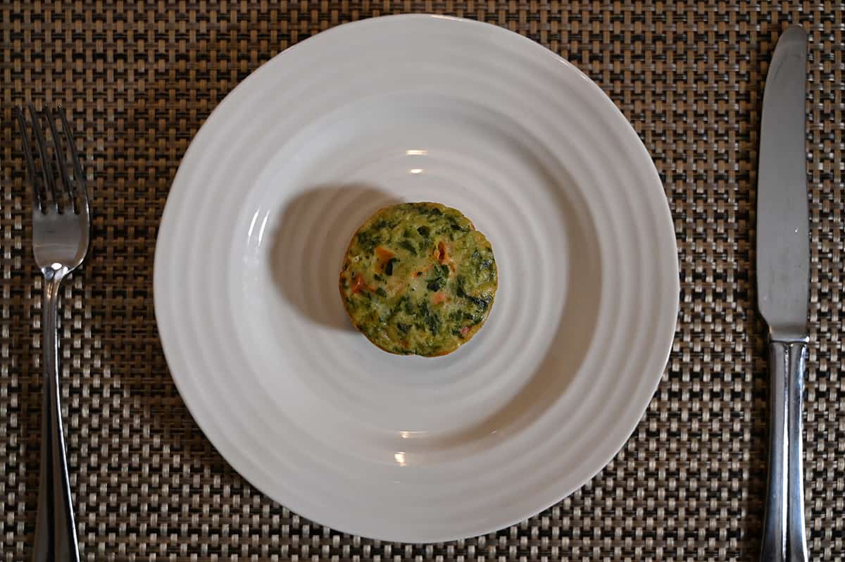Top down image of one cooked frittata sitting on a white plate.