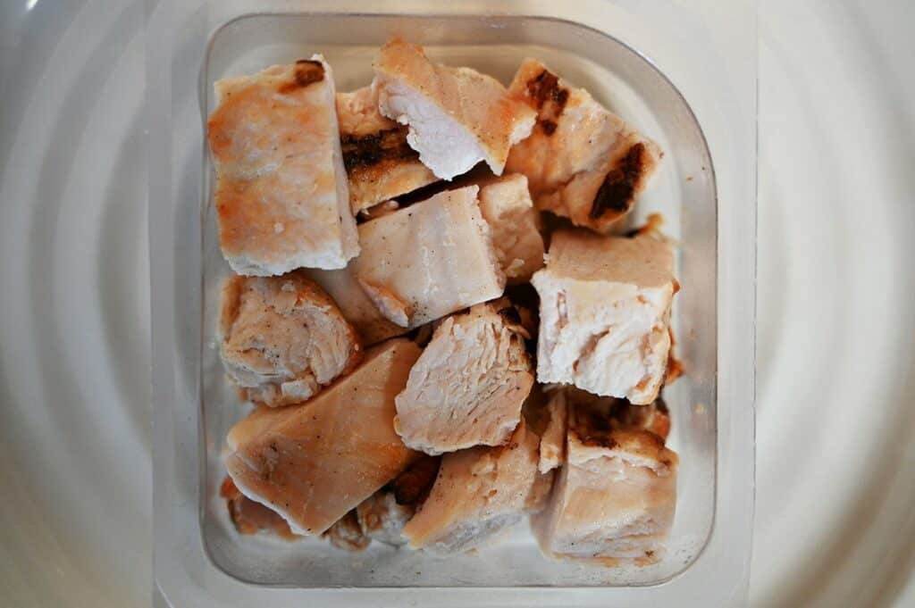 Costco Fresh Additions Fully Cooked Chicken Breast Bites Review 3 Costco Fresh Additions Fully Cooked Chicken Breast Bites single package on a white plate with lid off so you can see the chicken bites.