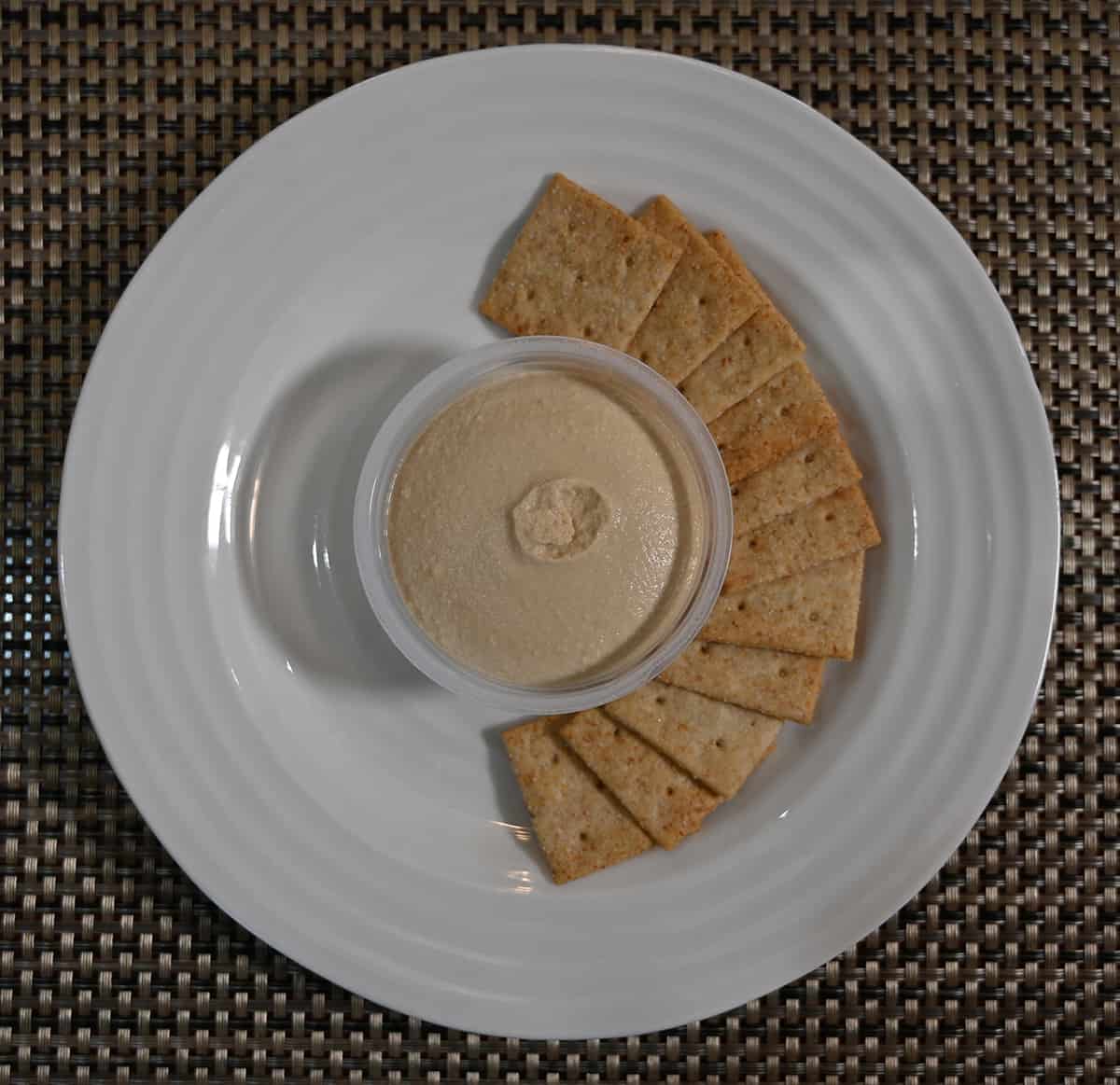 Top down image of a white plate with almond flour crackers served on it and hummus in the middle.