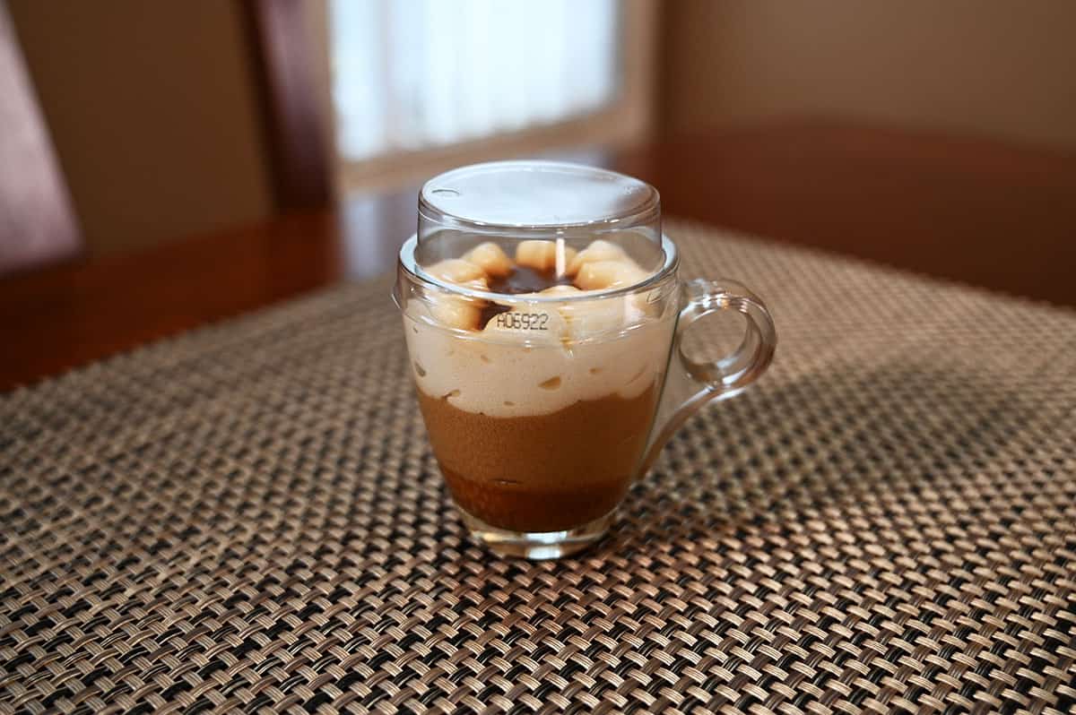 Image of the dessert in a little glass mug with a plastic lid.