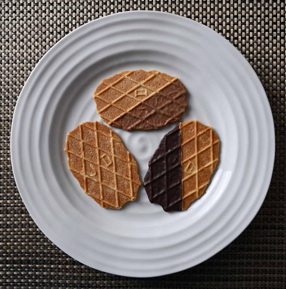 Top down image of three biscuits on a white plate, chocolate dipped, caramel and original butter biscuit.
