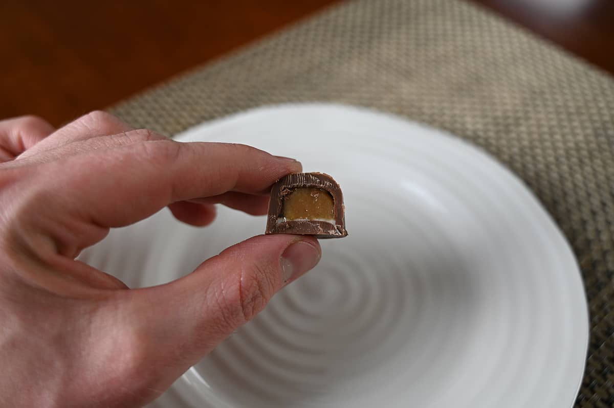 Image of a hand holding one Baileys chocolate with a bite taken out of it so you can see the center.