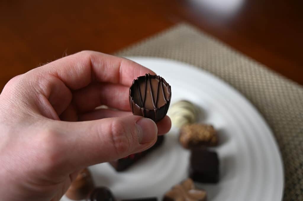 Image of a hand holding a rico chocolate close to the camera. 