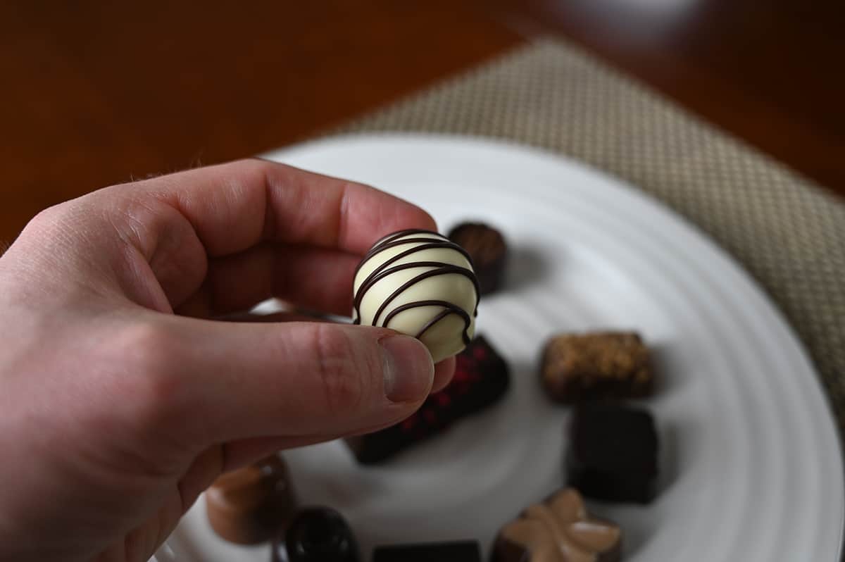 Image of a hand holding a manon chocolate close to the camera. 