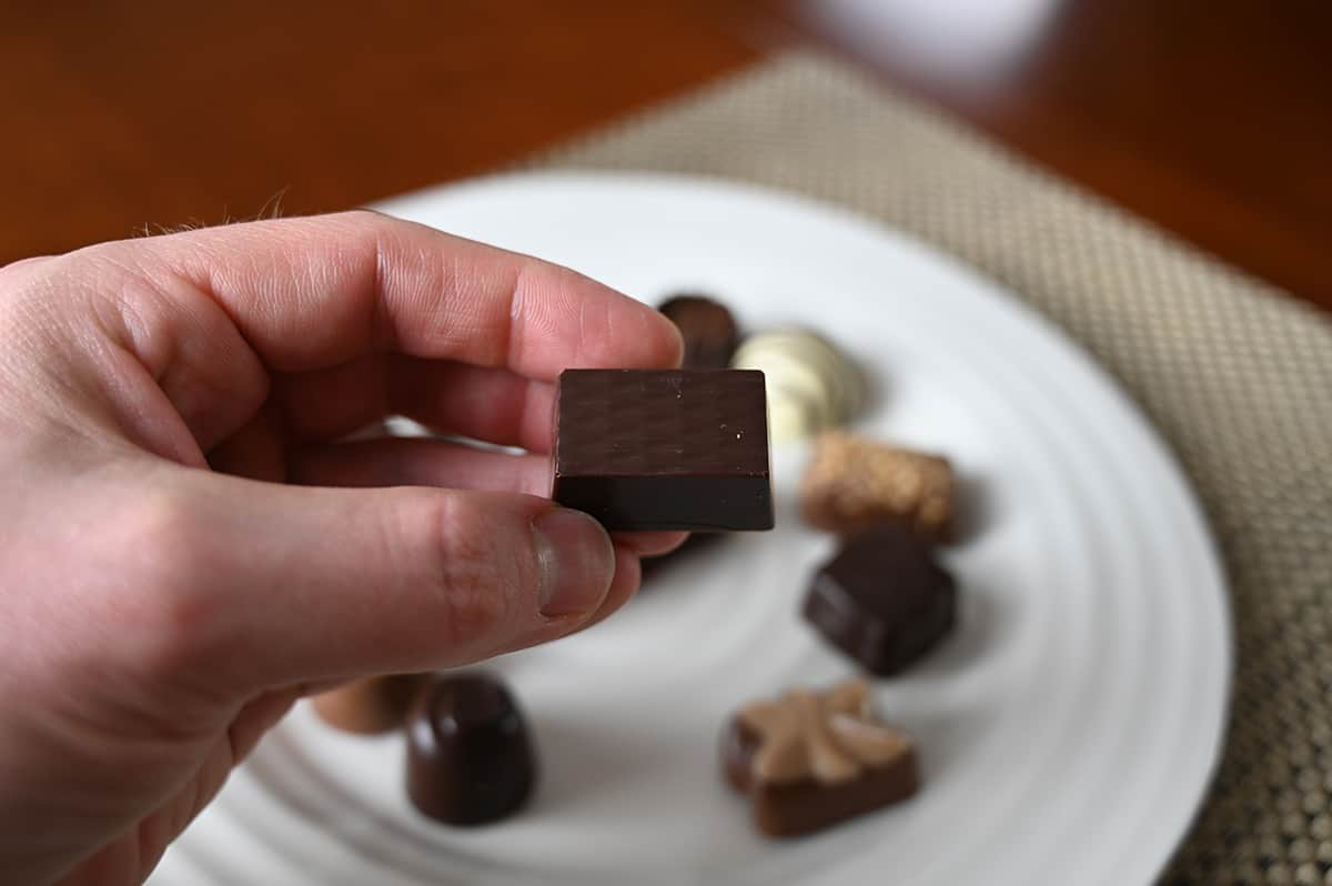 Image of a hand holding a Caresse chocolate close to the camera. 