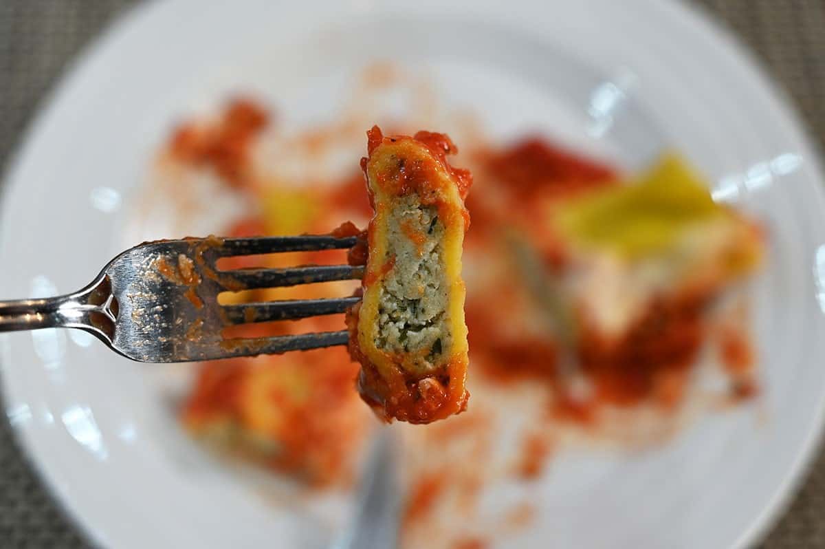Image of a closeup bite of the Costco Kirkland Signature Four Cheese and Spinach Manicotti so the inside filling is visible. 