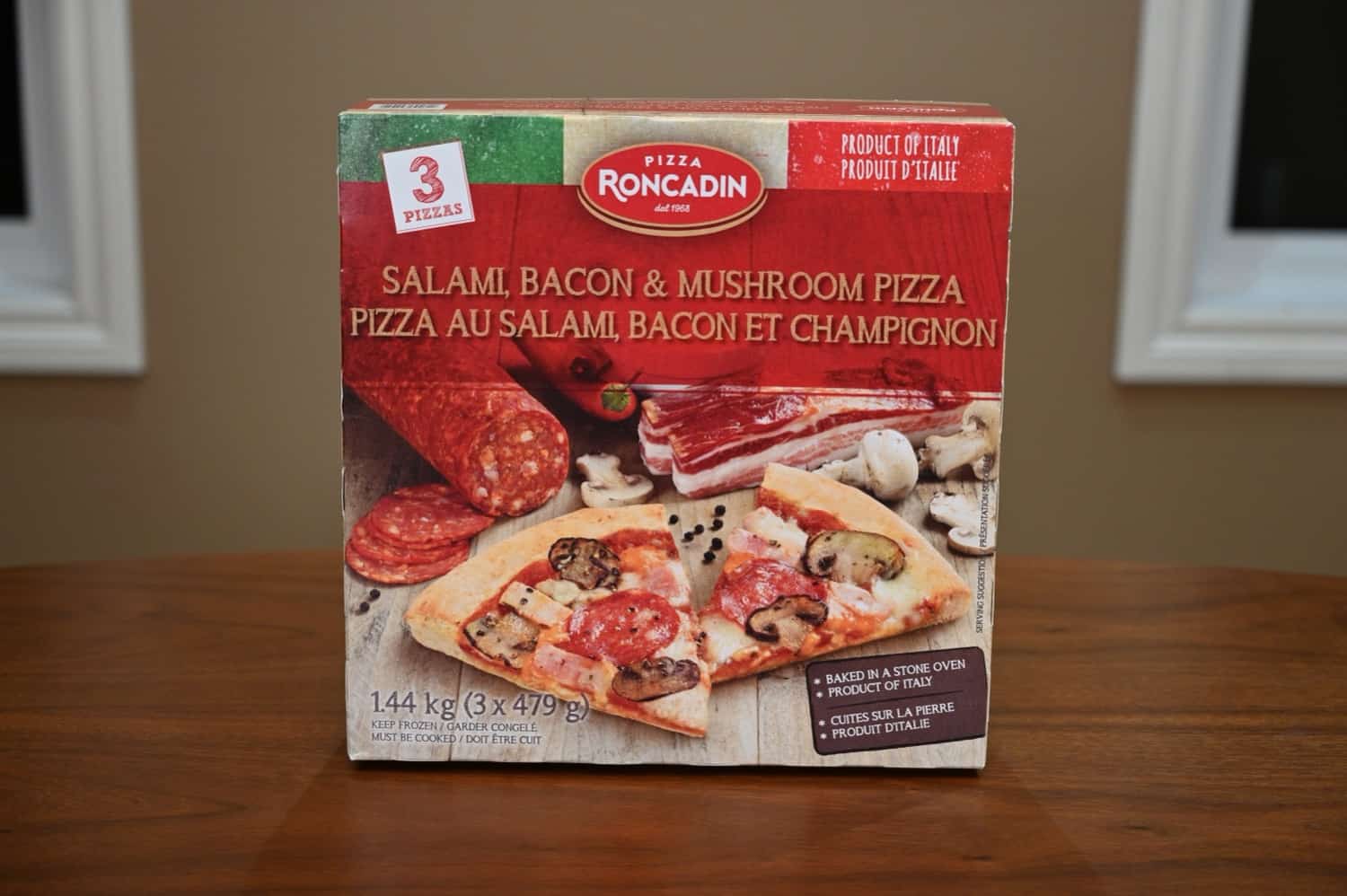 Image of a salami, bacon & mushroom pizza Rocadin box sitting unopened on a table.