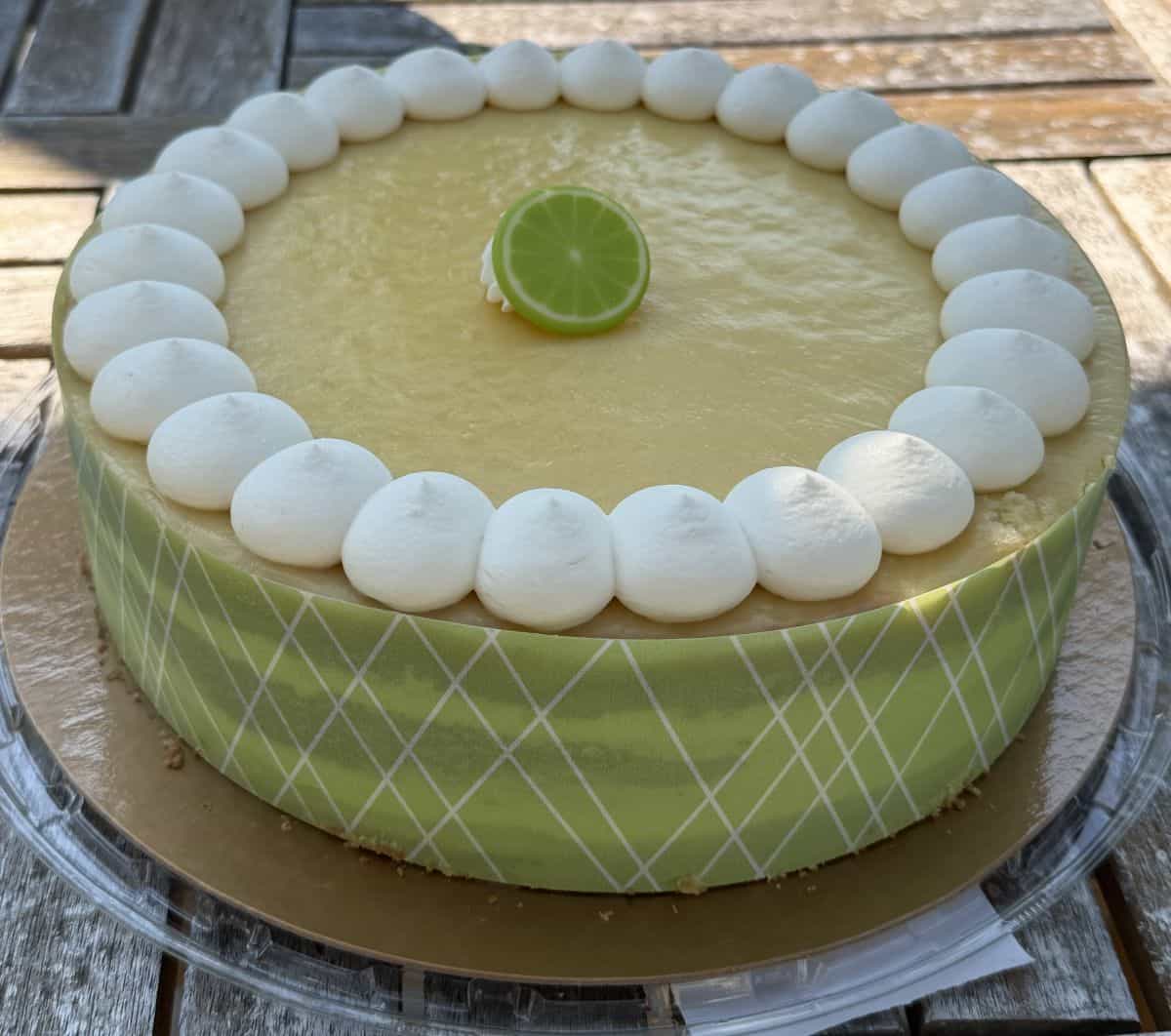 Closeup sideview image of the key lime cake with the wrapper on the side of the cake but the lid off.