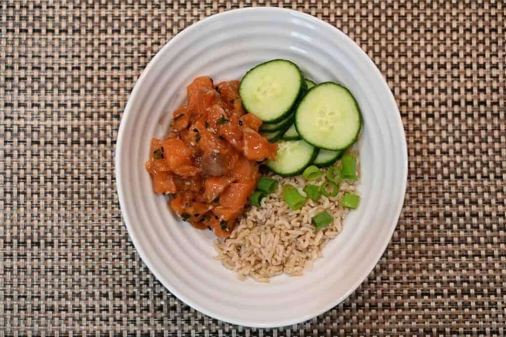 Costco Dom Reserve Singles Steelhead Salmon Poke in a bowl with rice, green onion and cucumber. 