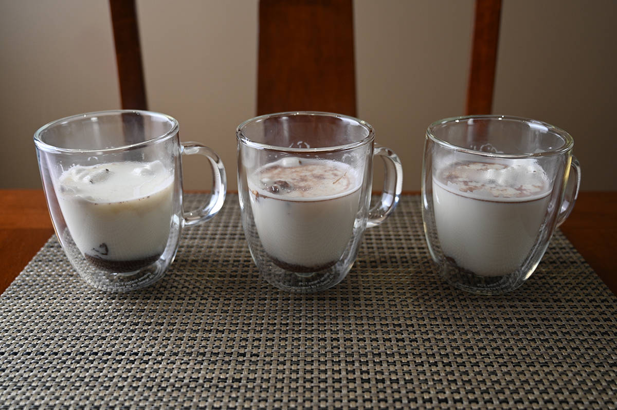 Image of the hot chocolate bombs in three clear mugs prior to mixing it in. You can see the chocolate on the bottom and marshmallows floating on top.