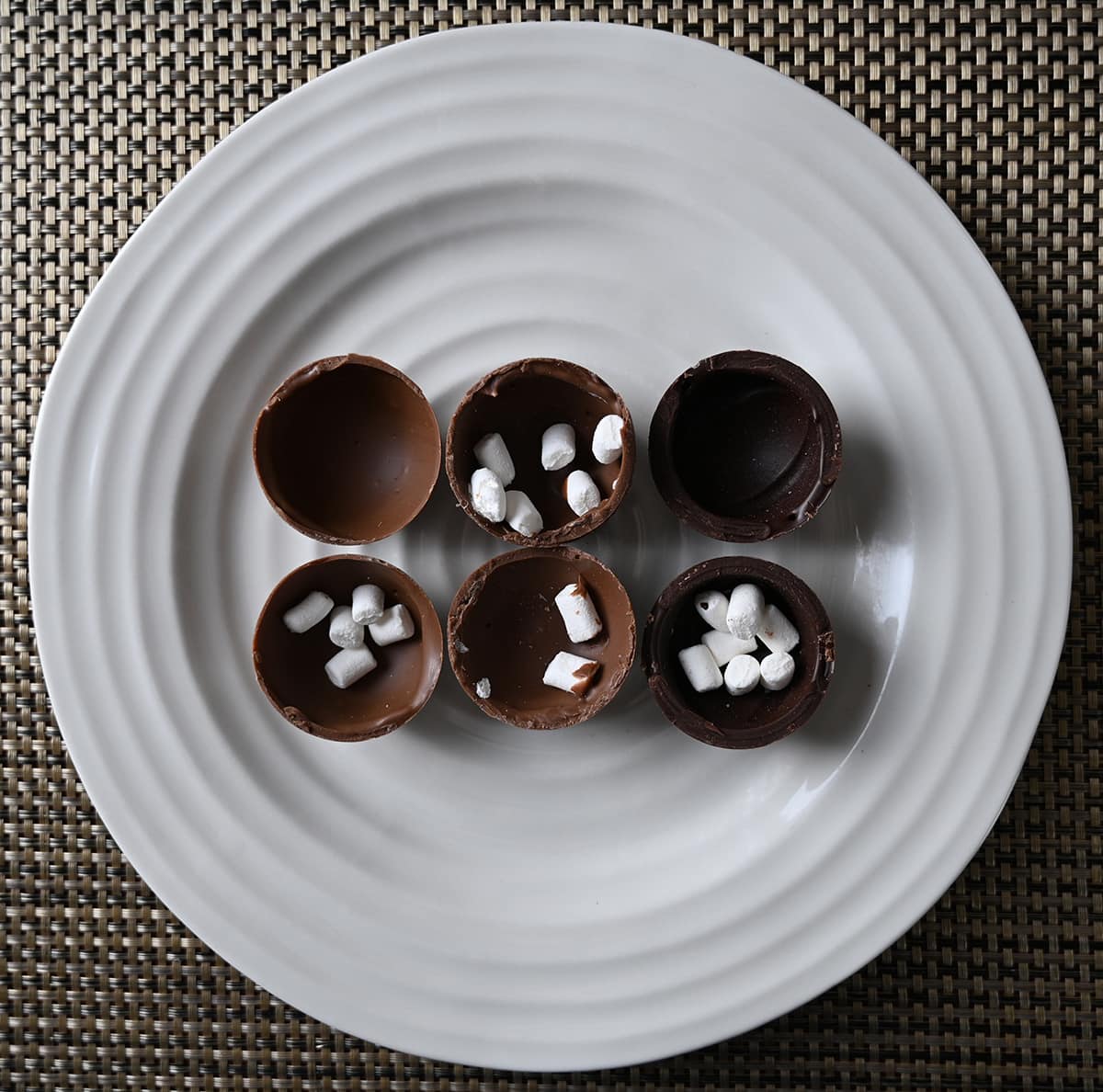 Image of three hot chocolate bombs unwrapped and cut in half so you can see that they are hollow with marshmallows in the middle.