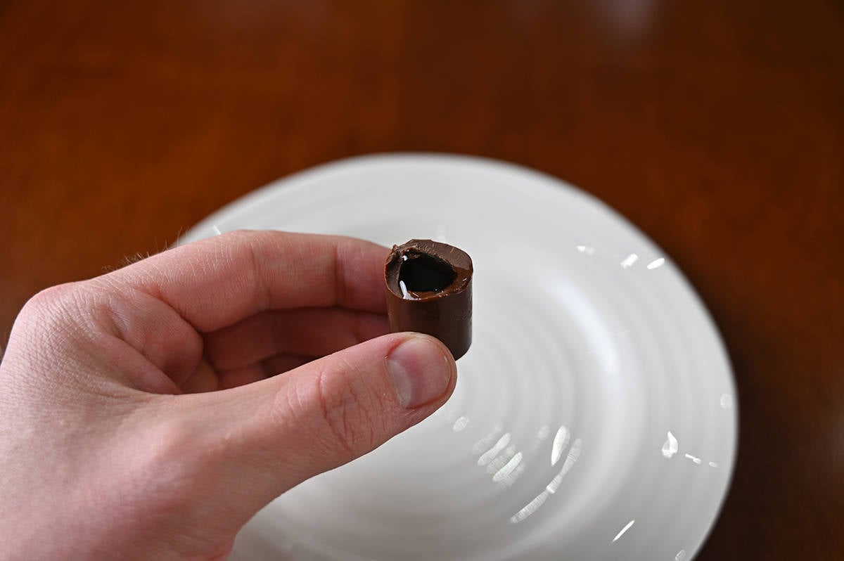 Image of a hand holding one liquor filled chocolate with a bite taken out of it so you can see the liquor inside.